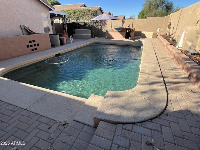 view of pool featuring a fenced in pool, a fenced backyard, a patio, and an outdoor kitchen