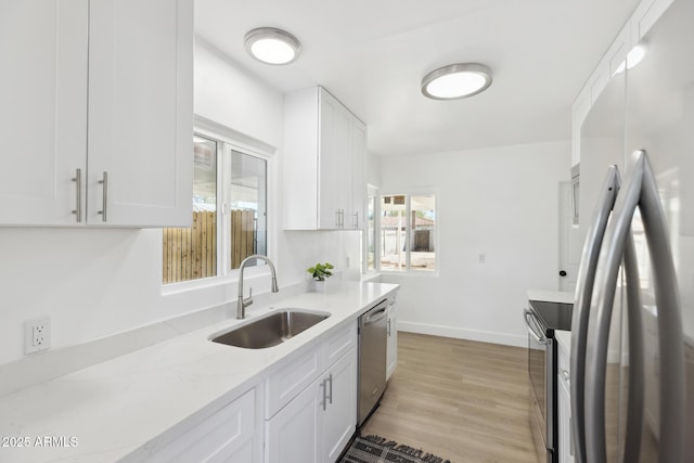 kitchen with a sink, light wood-type flooring, white cabinetry, and stainless steel appliances