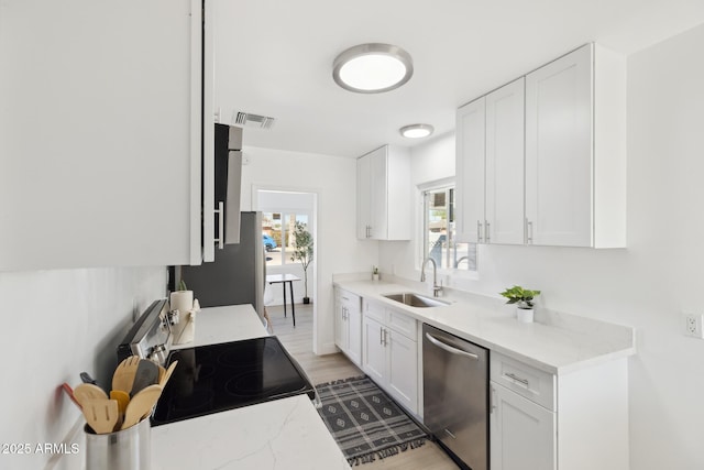 kitchen featuring visible vents, dishwasher, electric stove, white cabinetry, and a sink