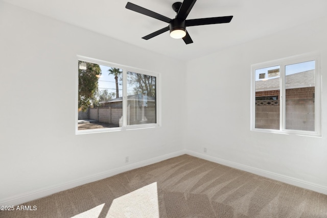 carpeted spare room with a ceiling fan and baseboards