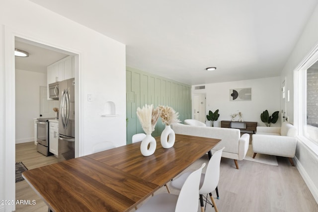 dining space featuring light wood-style floors, visible vents, and baseboards