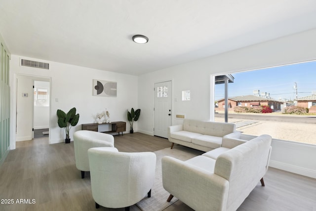 living room featuring visible vents, baseboards, and wood finished floors