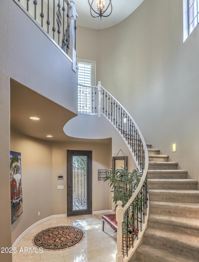 tiled entryway featuring an inviting chandelier, a wealth of natural light, and a high ceiling