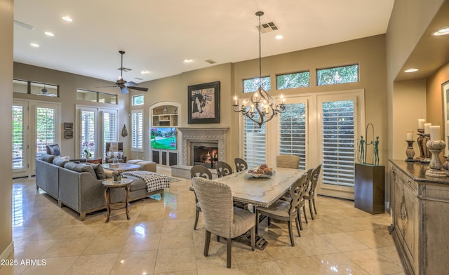 dining area with a premium fireplace, ceiling fan with notable chandelier, and light tile patterned flooring