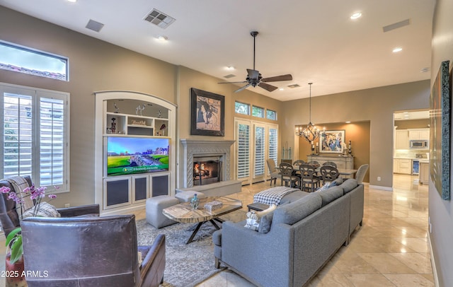 living room with ceiling fan with notable chandelier, a high end fireplace, and built in features