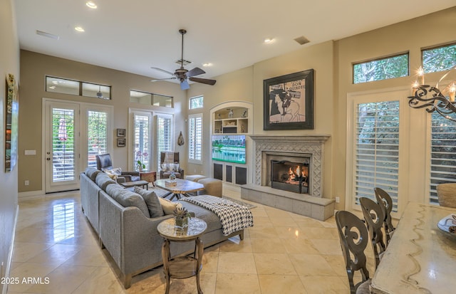 tiled living room featuring ceiling fan, a tiled fireplace, and built in features