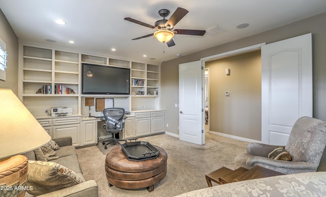 living room featuring built in features, built in desk, light colored carpet, and ceiling fan