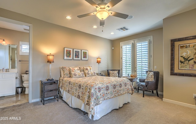 bedroom featuring ceiling fan, light colored carpet, and ensuite bath