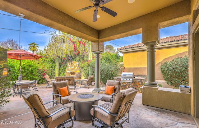 view of patio with an outdoor kitchen, ceiling fan, a grill, and a fire pit