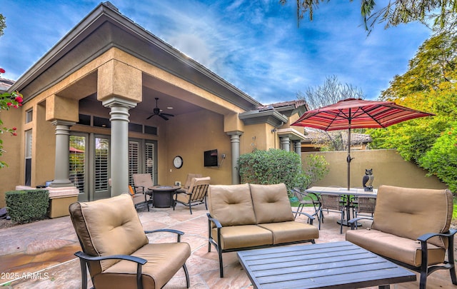 view of patio featuring ceiling fan and an outdoor living space with a fire pit