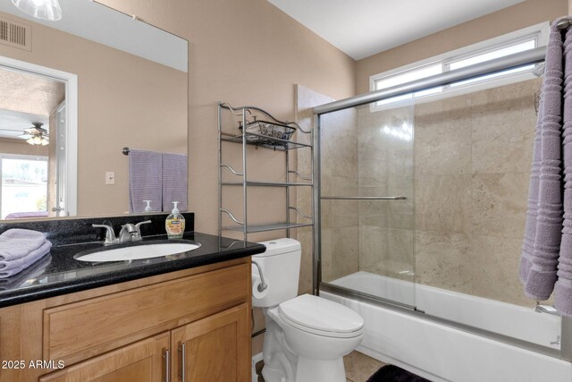 bathroom featuring healthy amount of natural light, toilet, vanity, and a ceiling fan