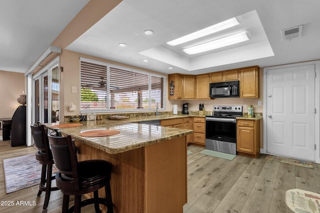kitchen with electric stove, black microwave, a tray ceiling, a peninsula, and recessed lighting