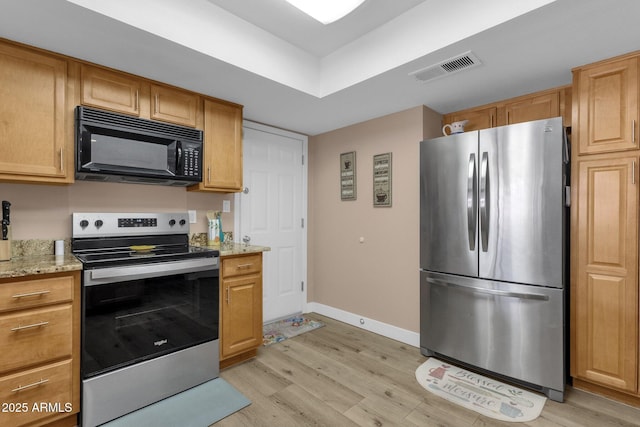 kitchen featuring stainless steel appliances, light wood-type flooring, light stone countertops, and baseboards
