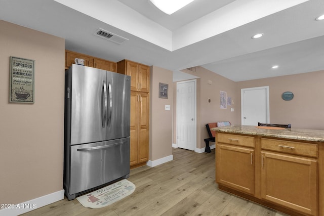 kitchen featuring freestanding refrigerator, light wood finished floors, baseboards, recessed lighting, and light stone counters