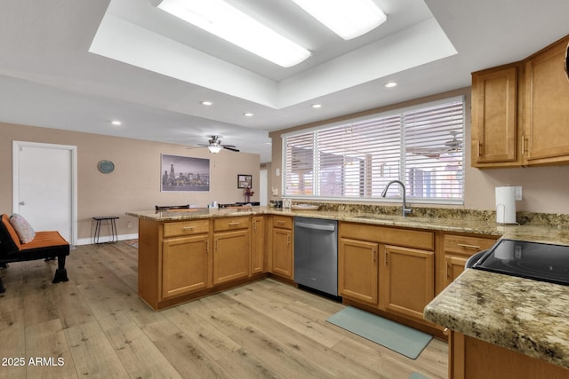 kitchen with dishwasher, a peninsula, light wood-type flooring, a sink, and a raised ceiling
