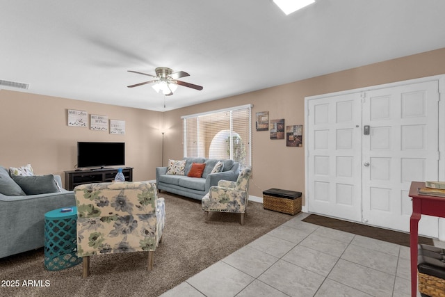 living area featuring carpet floors, ceiling fan, tile patterned flooring, and baseboards