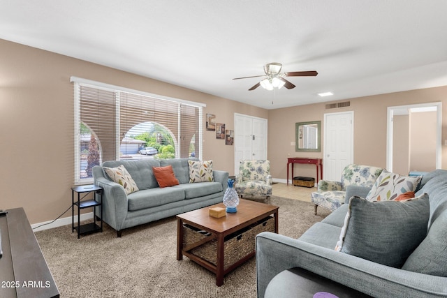 living room featuring a ceiling fan, baseboards, and light colored carpet