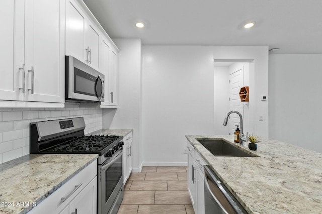 kitchen featuring backsplash, light stone counters, stainless steel appliances, sink, and white cabinets