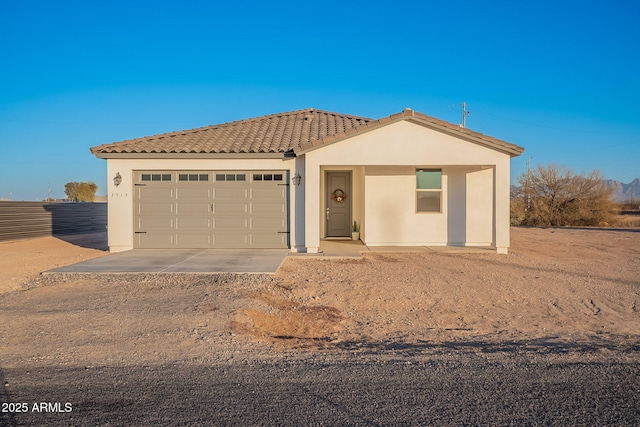 view of front of house with driveway, stucco siding, a tiled roof, and a garage