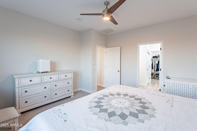 carpeted bedroom featuring a spacious closet, a closet, and ceiling fan