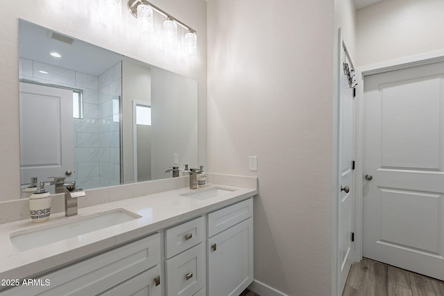 bathroom featuring hardwood / wood-style floors, vanity, and a tile shower