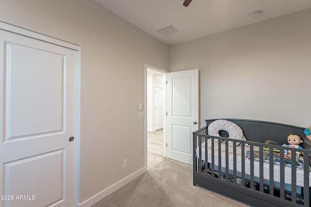 carpeted bedroom featuring ceiling fan and a crib