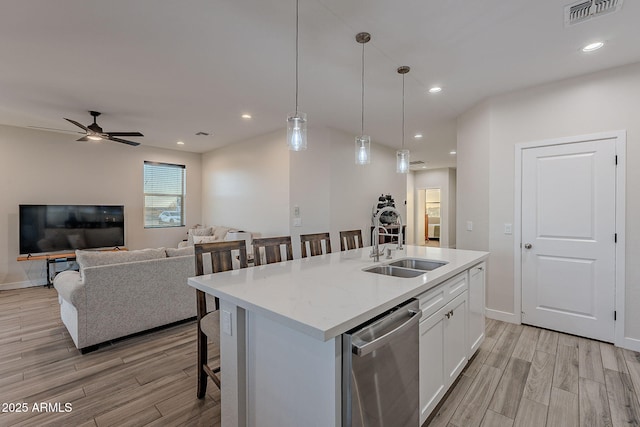 kitchen featuring pendant lighting, dishwasher, white cabinetry, a breakfast bar, and a center island with sink