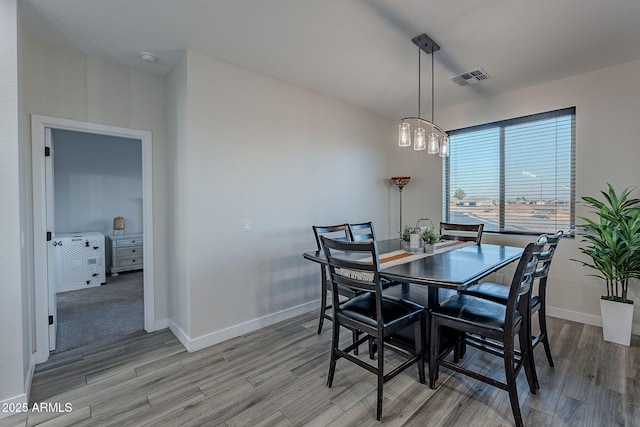 dining area with light hardwood / wood-style floors and a notable chandelier