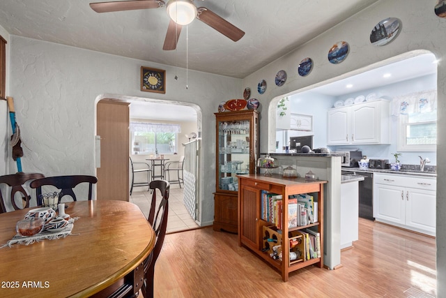 kitchen with sink, white cabinetry, stainless steel dishwasher, ceiling fan, and light hardwood / wood-style floors