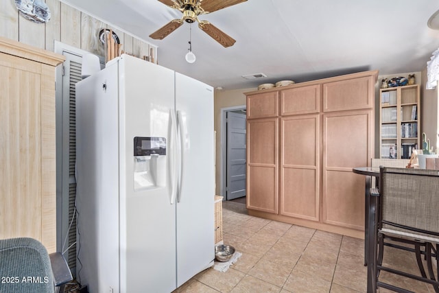 kitchen with light tile patterned flooring, white refrigerator with ice dispenser, light brown cabinetry, and ceiling fan