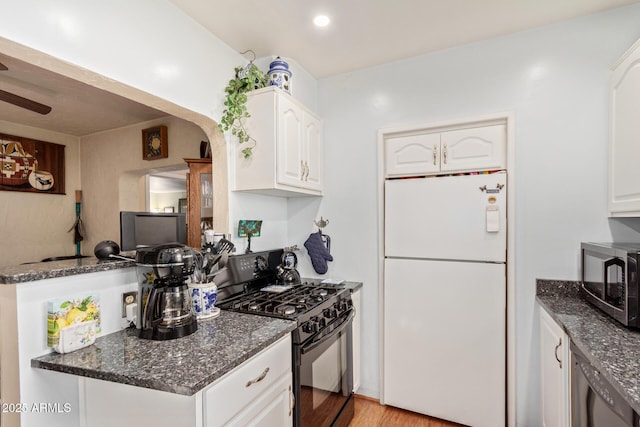 kitchen with white cabinetry, dark stone countertops, white refrigerator, black range with gas stovetop, and ceiling fan