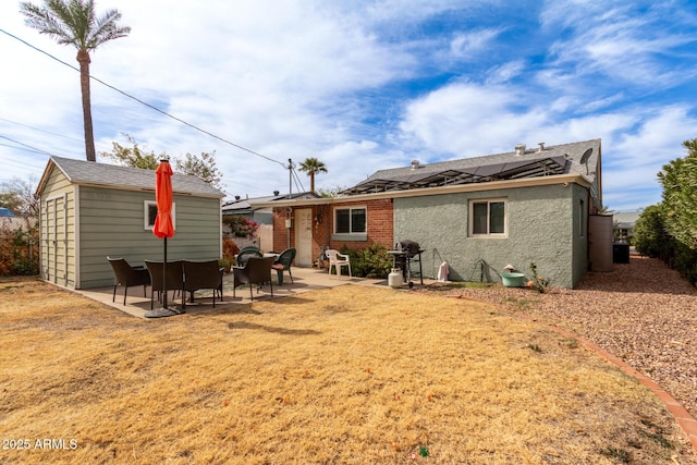 back of property featuring an outdoor structure, a patio area, and solar panels