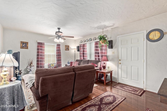 living room with hardwood / wood-style flooring, ceiling fan, and a textured ceiling