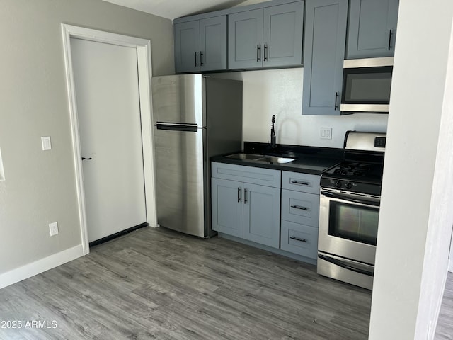 1917 E Monroe St, Phoenix, AZ 85034 - kitchen featuring appliances with stainless steel finishes, dark countertops, a sink, wood finished floors, and baseboards