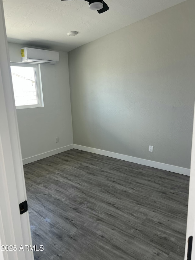1917 E Monroe St, Phoenix, AZ 85034 - unfurnished room with a wall unit AC, baseboards, dark wood-type flooring, and a textured ceiling