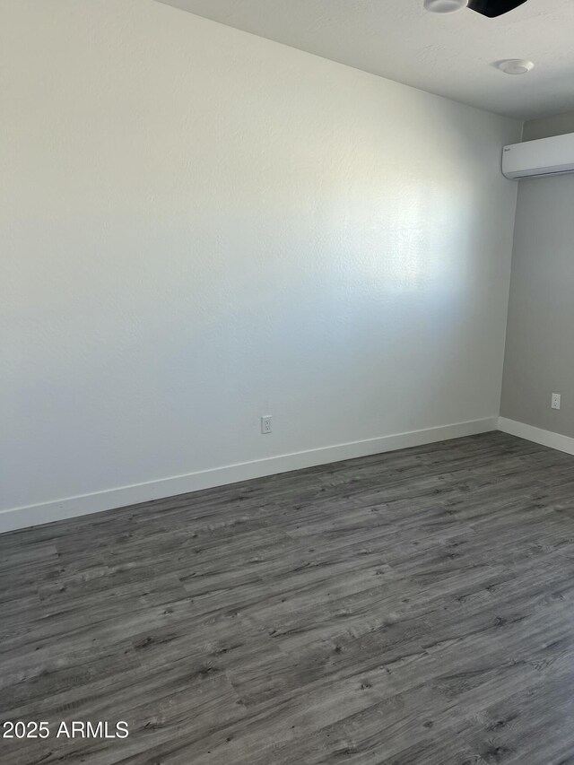 1917 E Monroe St, Phoenix, AZ 85034 - empty room featuring baseboards, a wall mounted air conditioner, and dark wood-type flooring