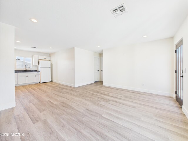 1917 E Monroe St, Phoenix, AZ 85034 - unfurnished living room featuring a sink, recessed lighting, light wood-style floors, and baseboards