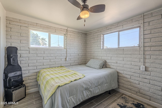 bedroom featuring multiple windows and brick wall