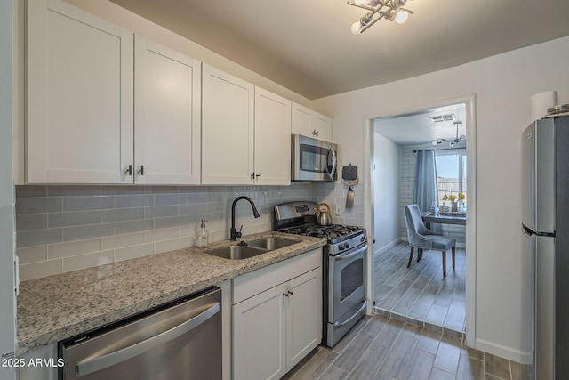 kitchen featuring light stone counters, sink, stainless steel appliances, and white cabinets