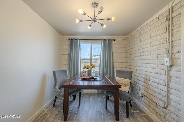 dining room featuring an inviting chandelier and brick wall