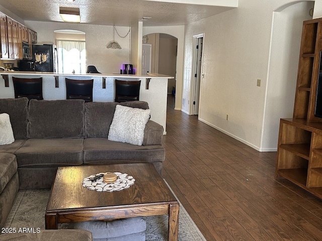 8981 W Tuckey Ln, Glendale, AZ 85305 - living room with arched walkways, dark wood-type flooring, baseboards, and a textured ceiling