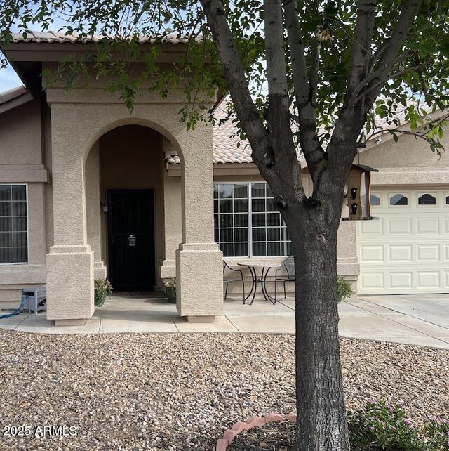 8981 W Tuckey Ln, Glendale, AZ 85305 - property entrance with stucco siding, a tiled roof, and a garage