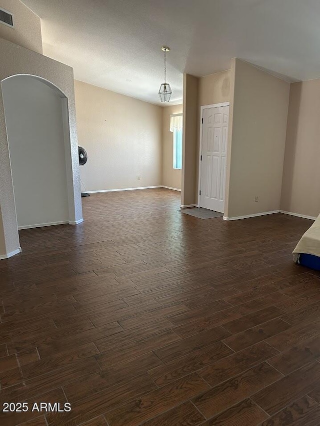 8981 W Tuckey Ln, Glendale, AZ 85305 - spare room featuring dark wood-type flooring, arched walkways, and baseboards