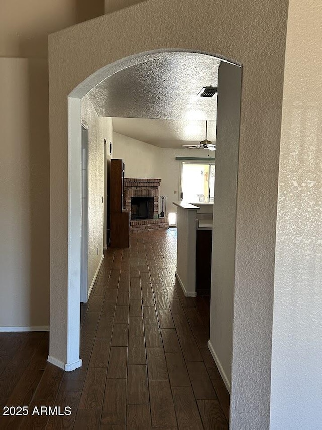 8981 W Tuckey Ln, Glendale, AZ 85305 - hallway with a textured wall, dark wood-style flooring, arched walkways, and baseboards