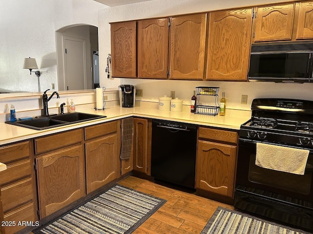 8981 W Tuckey Ln, Glendale, AZ 85305 - kitchen with black appliances, a sink, wood finished floors, light countertops, and a textured wall