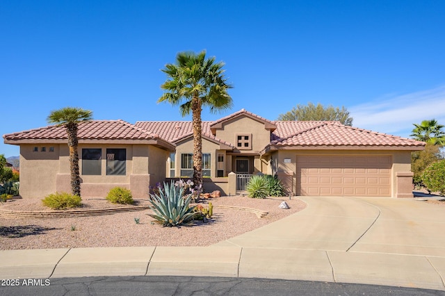 mediterranean / spanish-style house featuring concrete driveway, a tiled roof, an attached garage, and stucco siding