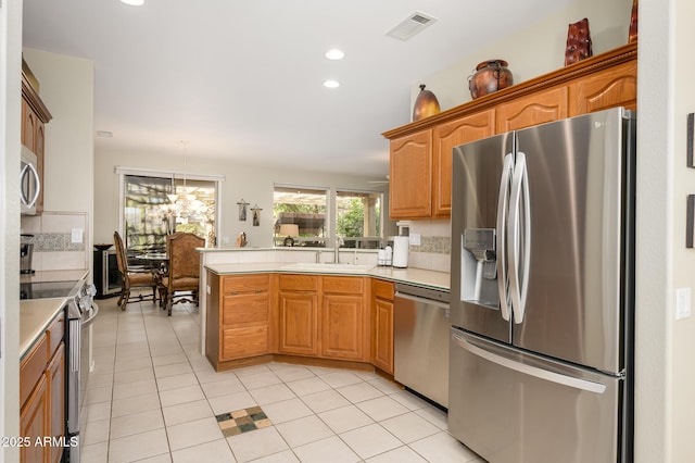 kitchen with light countertops, appliances with stainless steel finishes, a peninsula, and visible vents