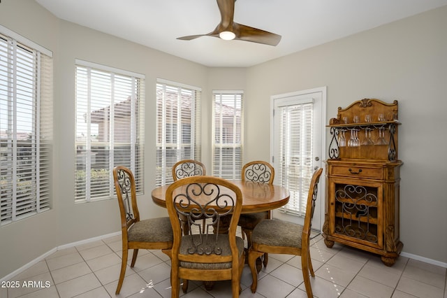 dining area featuring baseboards, light tile patterned flooring, a ceiling fan, and a healthy amount of sunlight