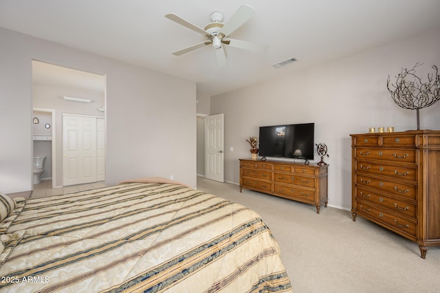 bedroom with a ceiling fan, ensuite bath, visible vents, and light colored carpet