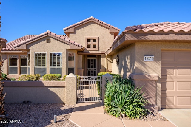 mediterranean / spanish house with a garage, a gate, fence, and stucco siding